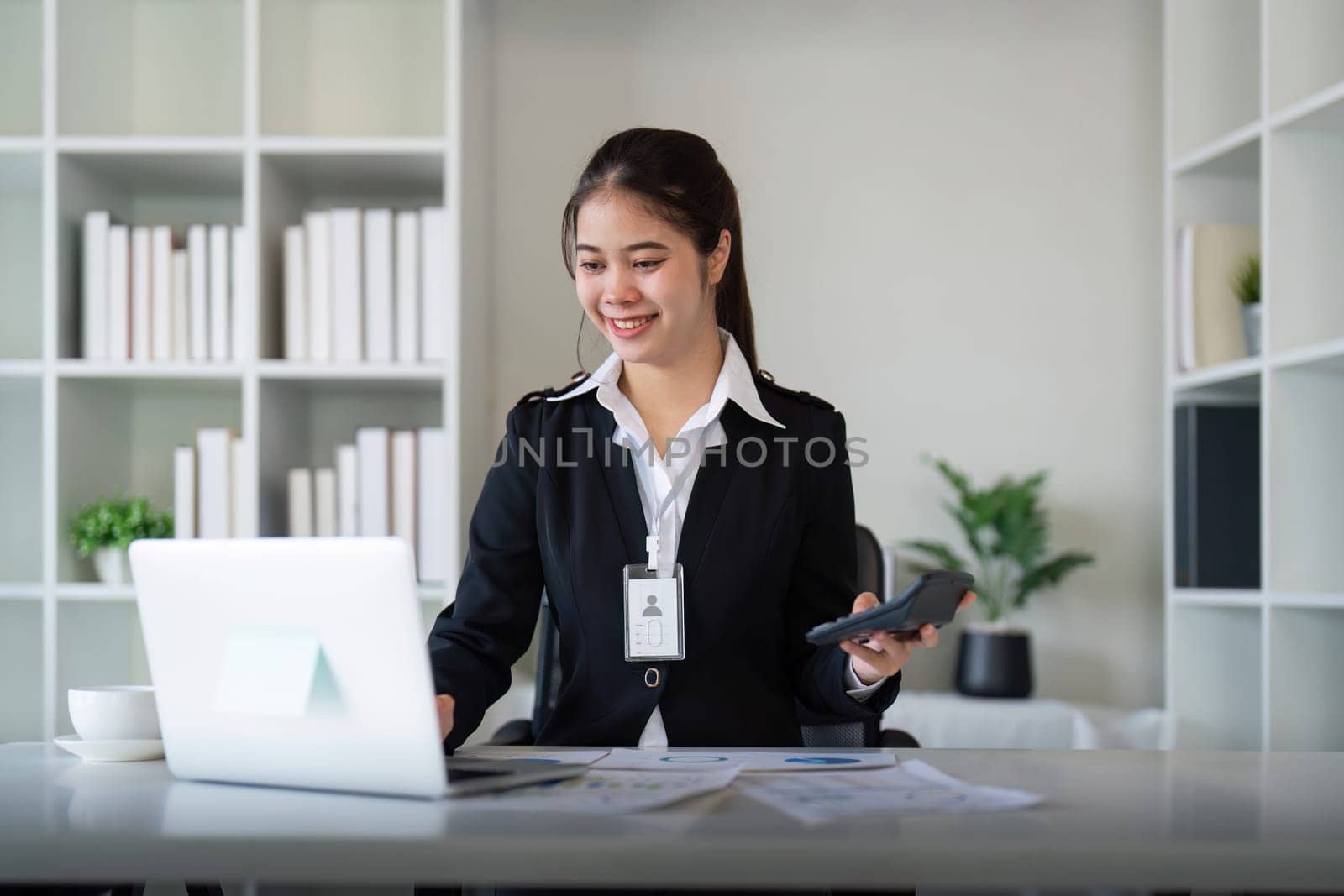 Charming Asian business woman sitting working on laptop in office.