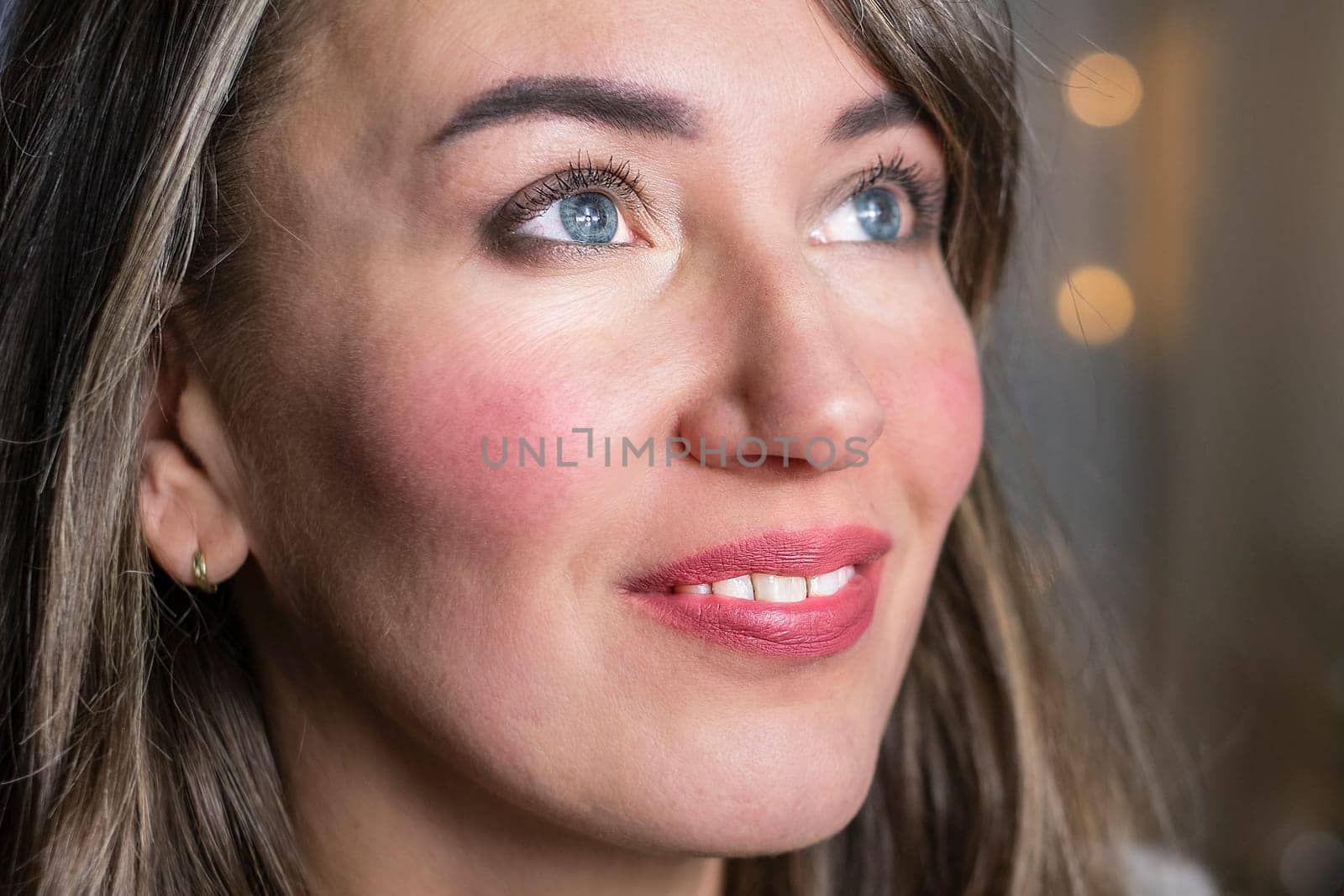 Closeup portrait of young happy smiling woman with glowing eyes looking up.