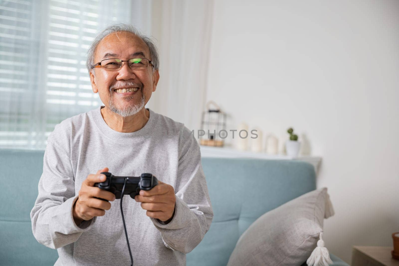 Funny retirement elderly smile sitting on sofa life gaming by Sorapop