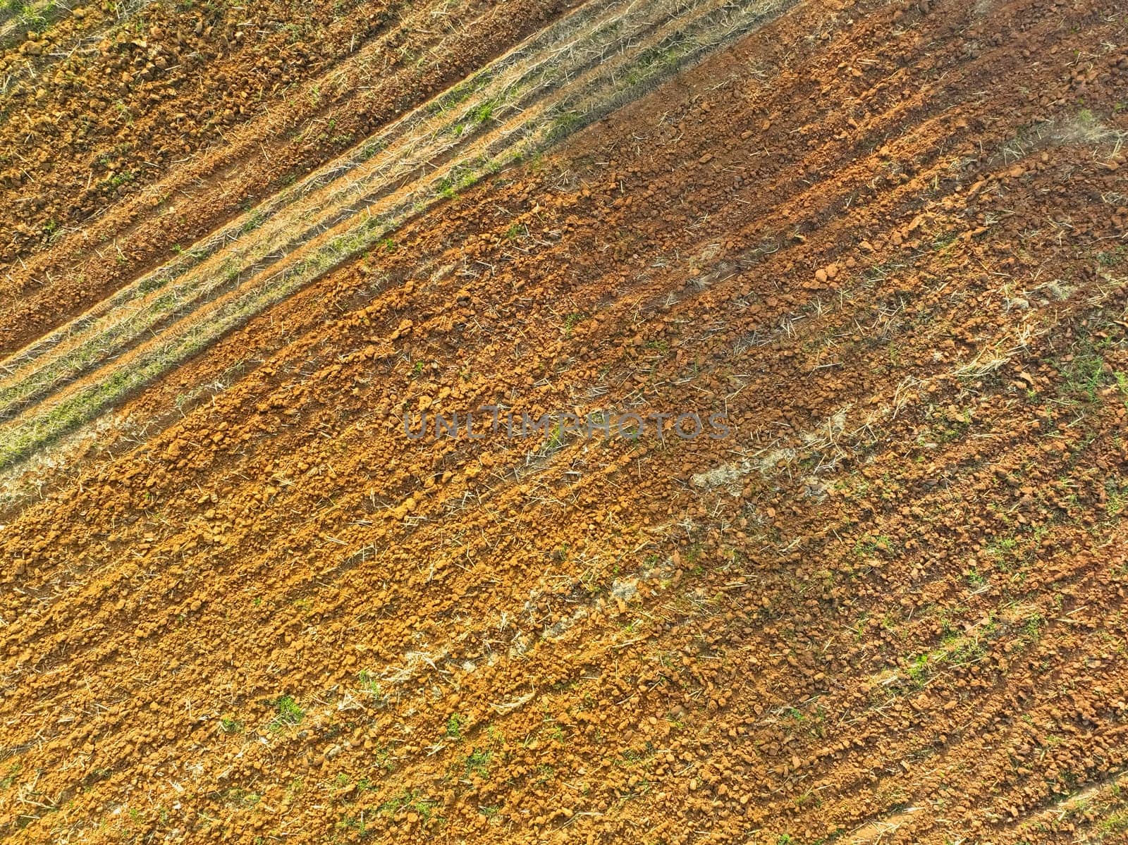 Aerial view of agriculture plowed field. Minimal tillage for healthier soils. Fertile soil in organic agricultural farm. Soil conservation. Sustainable agriculture. Soil fertility. Plowed land. by Fahroni