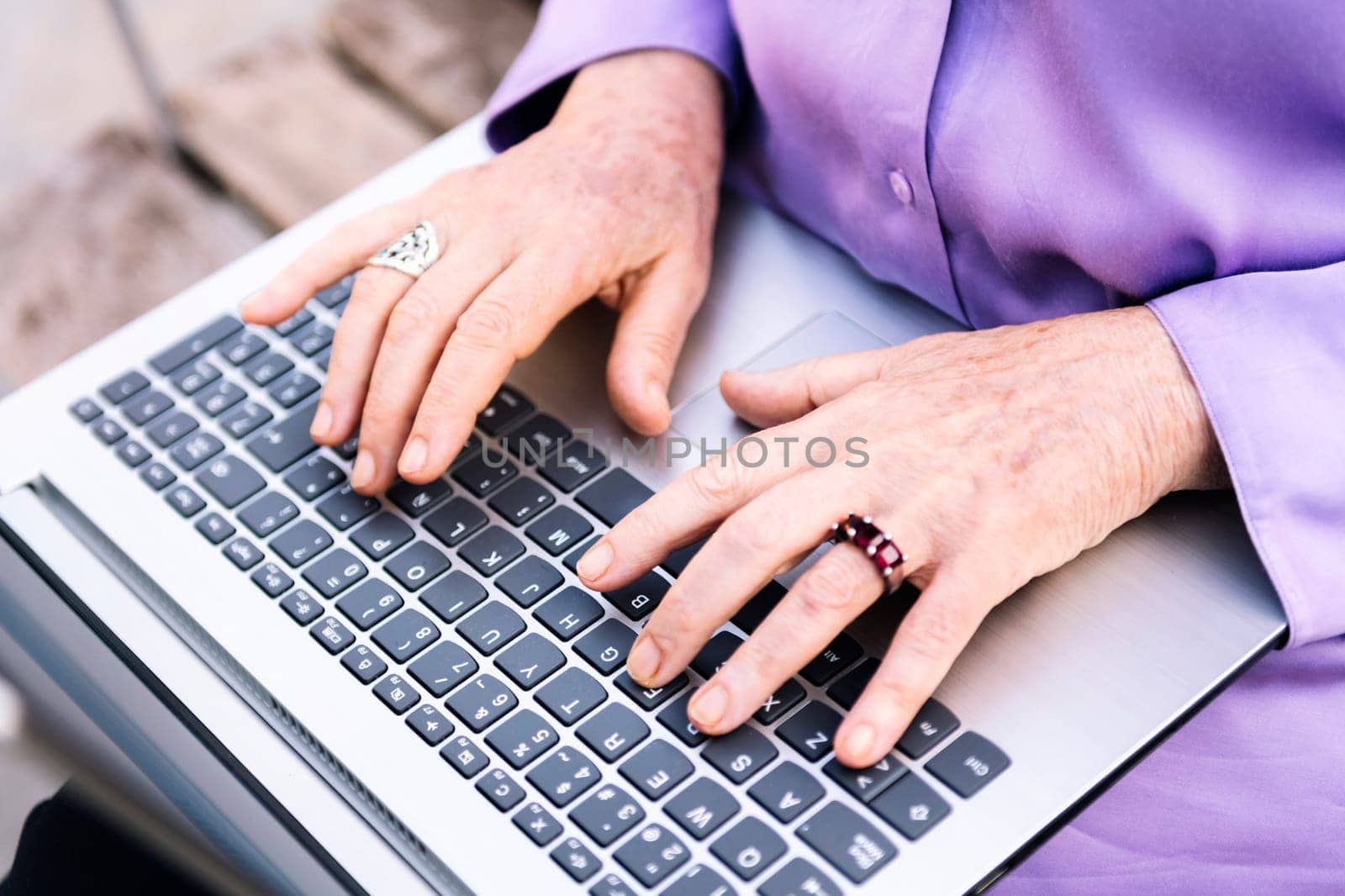 hands of a senior woman typing on a laptop by raulmelldo