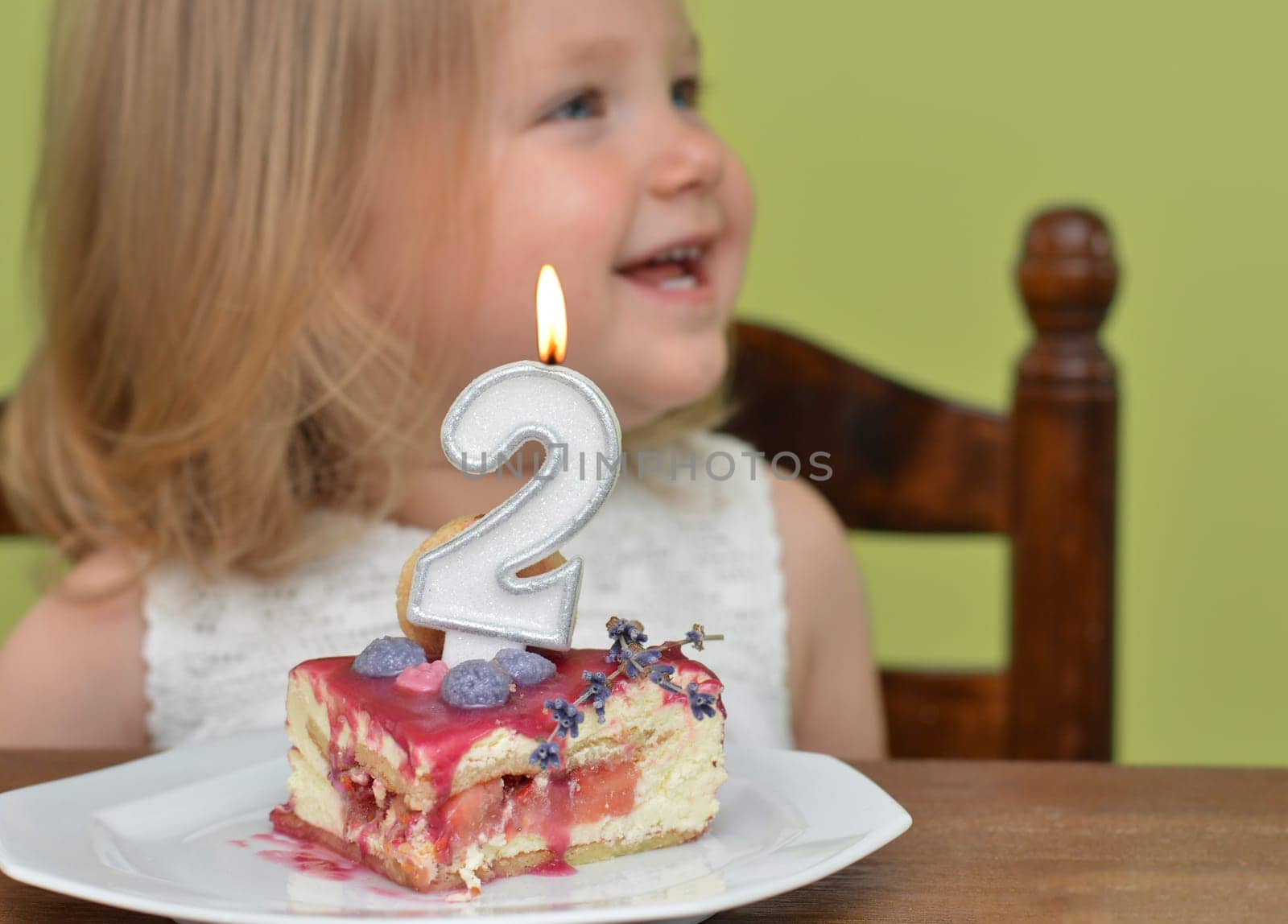 Cut slice of birthday cake 2 years Small girl on a background
