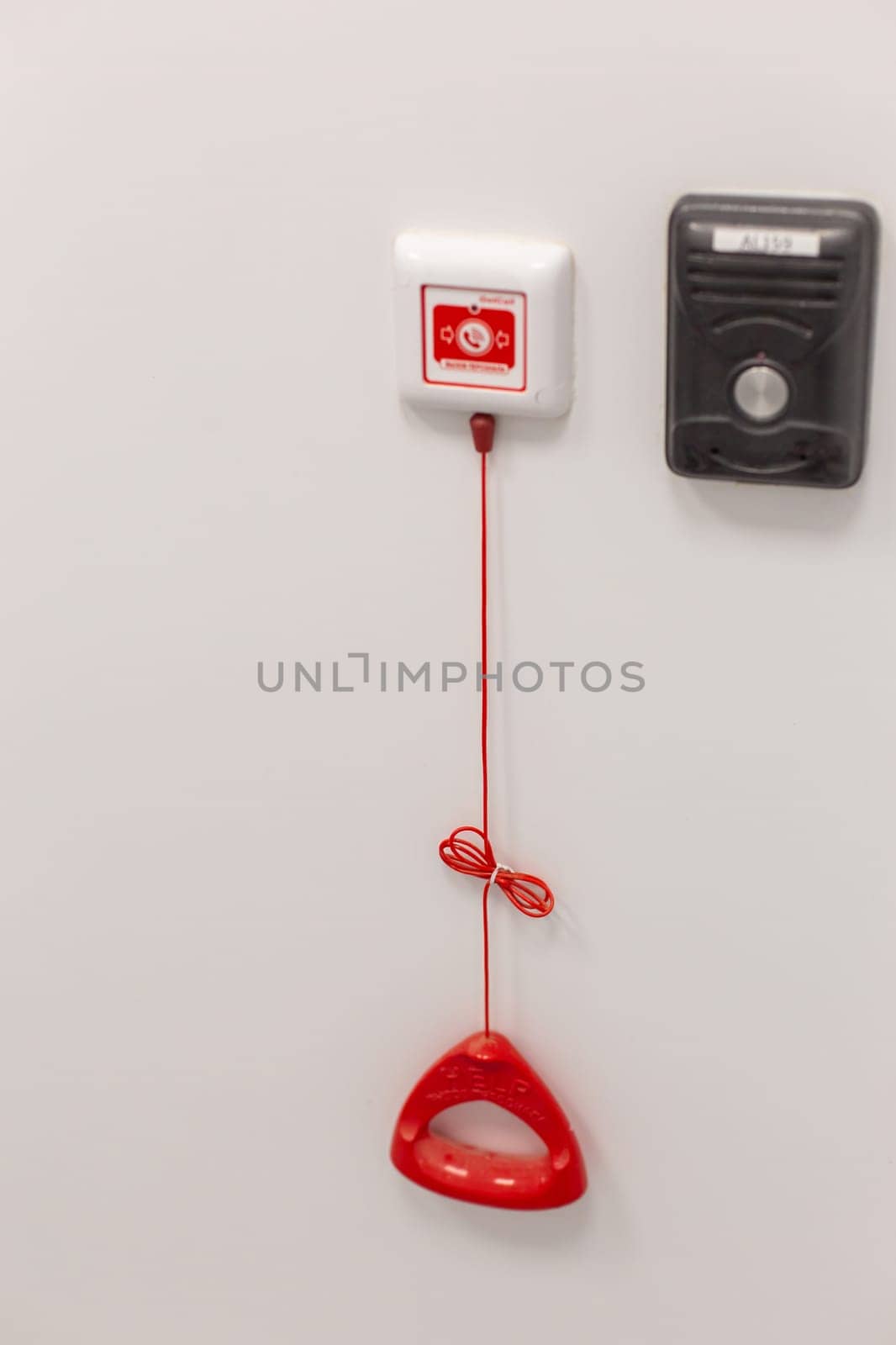 A red emergency pull cord system on a white wall in a clinical setting.