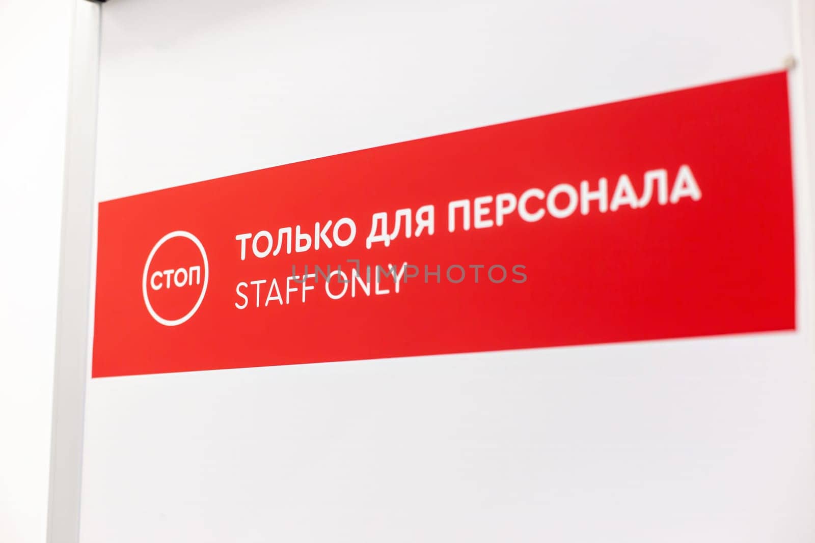 Red and white 'Staff Only' sign with bilingual text in English and Russian above door by Zakharova