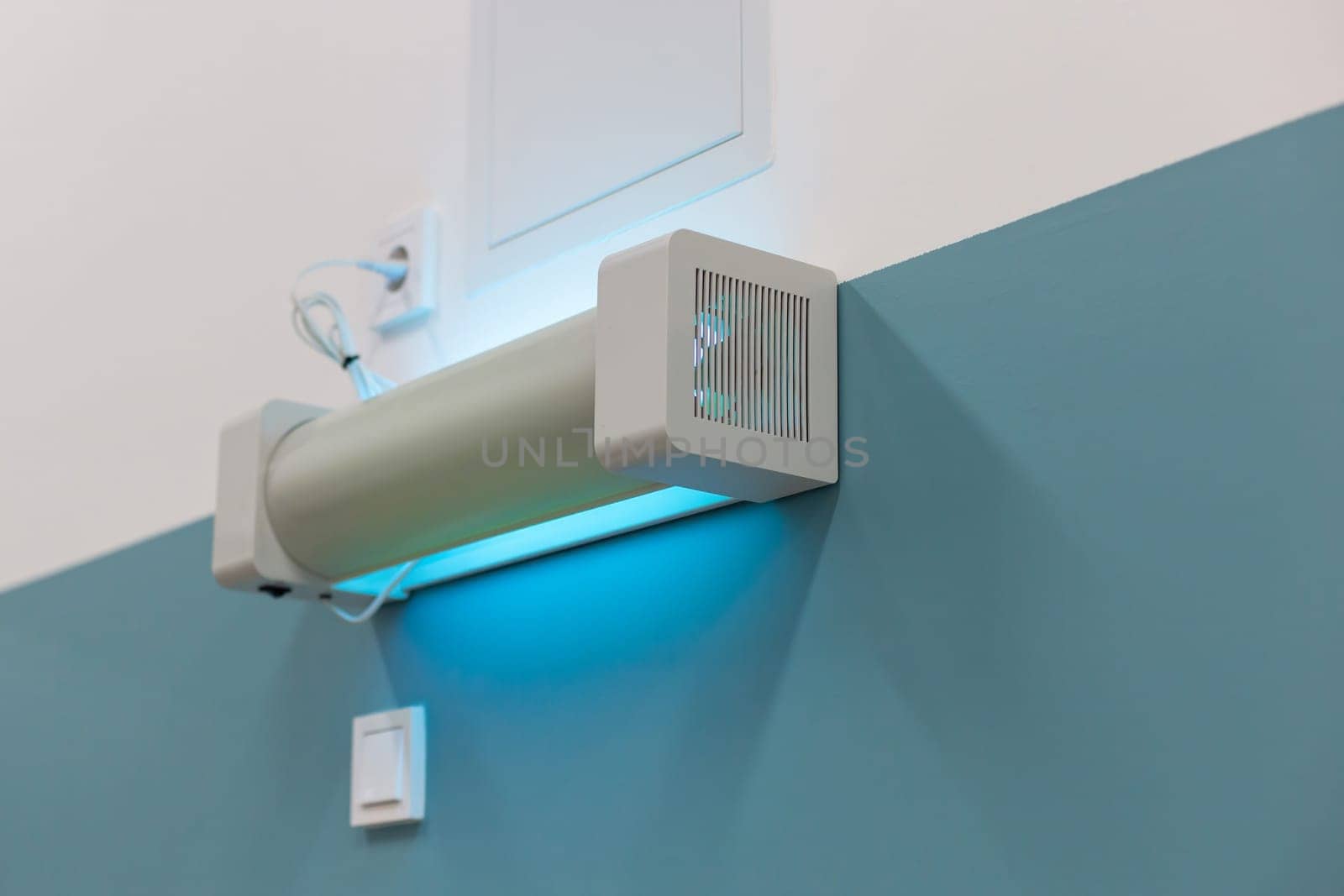 Wall-mounted UV sterilization lamp emitting blue light for disinfection in a hospital setting by Zakharova