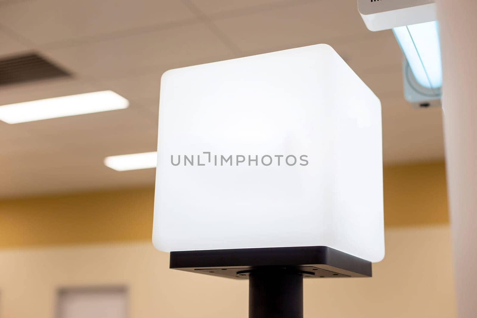 White empty light information cube on the counter, with a place for text, in a room with artificial light. Copy space