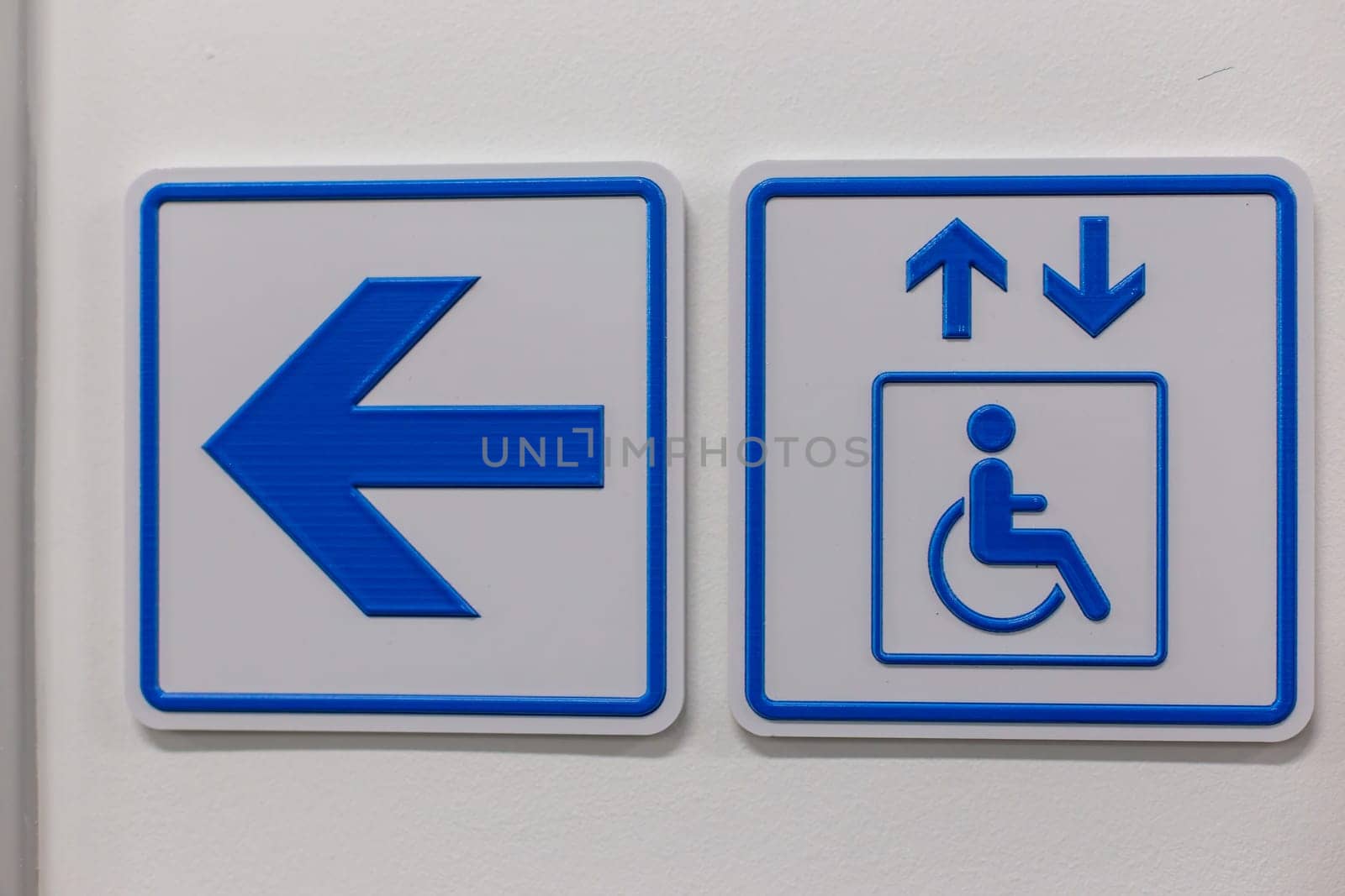 A blue arrow and elevator access signs disabled person on the wall.