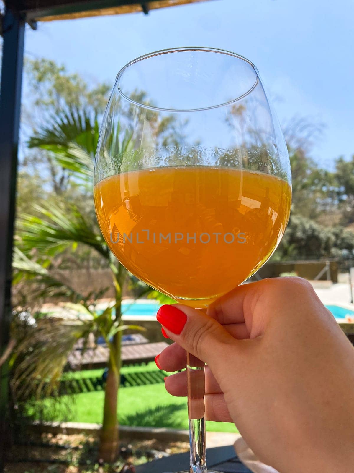 Woman with red nail manicure holding a glass of orange juice in their hand, palms on the background. High quality photo