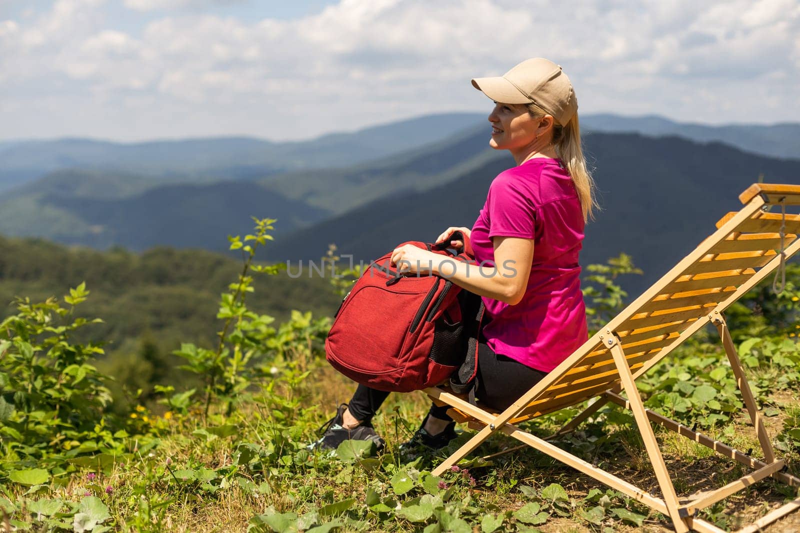 stylish traveler woman relaxing in mountains. hipster on top of mountain, resting. space for text. atmospheric moment. wanderlust and travel concept