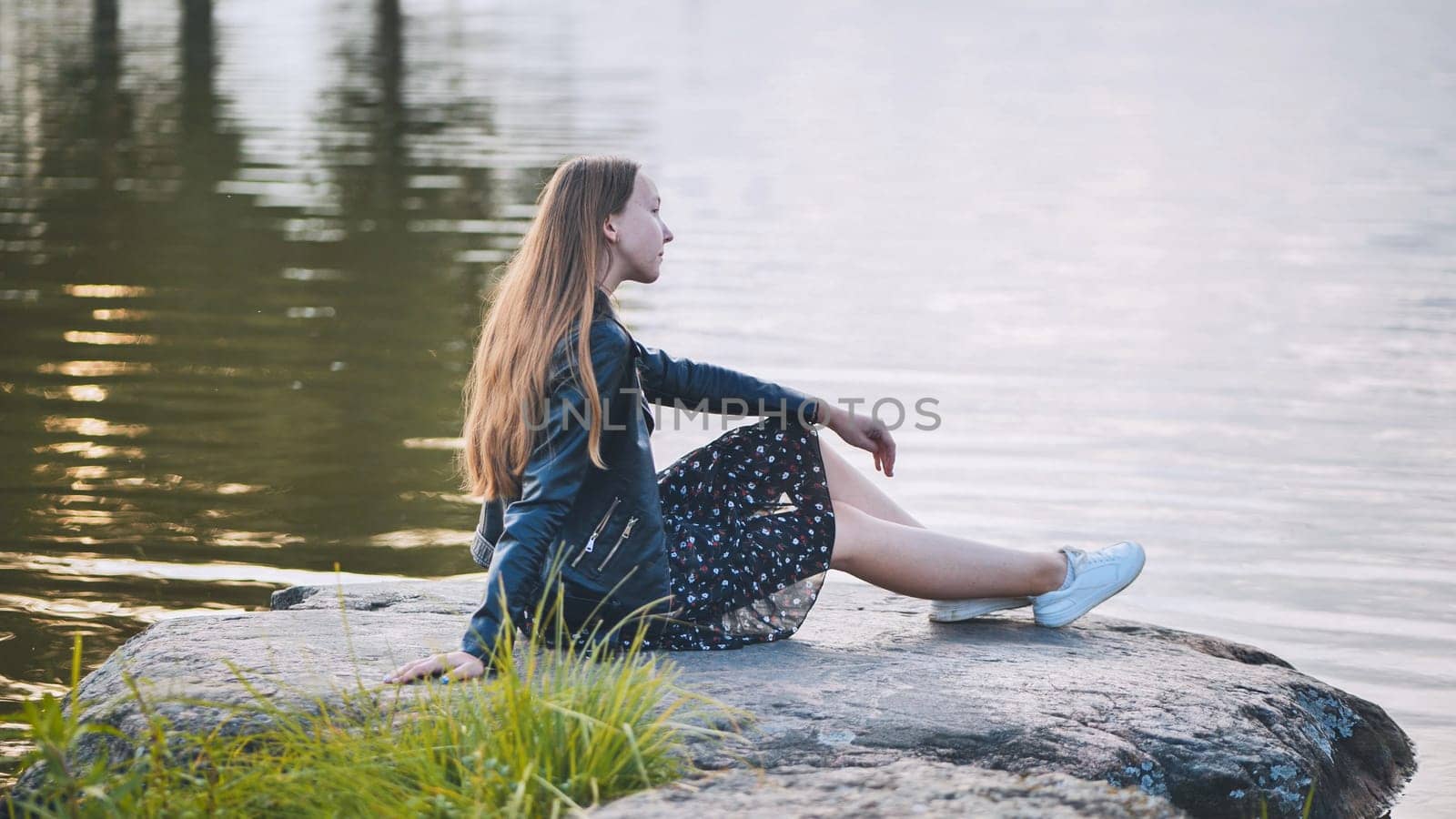 A girl sits by the lake on a rock. by DovidPro