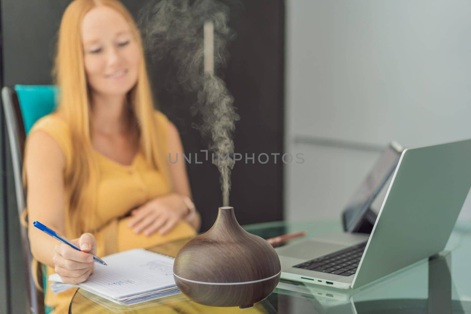 Expectant woman enhances work environment, using an aroma diffuser for a soothing atmosphere during pregnancy by galitskaya