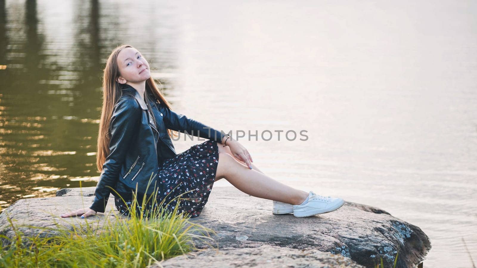 A girl sits by the lake on a rock. by DovidPro