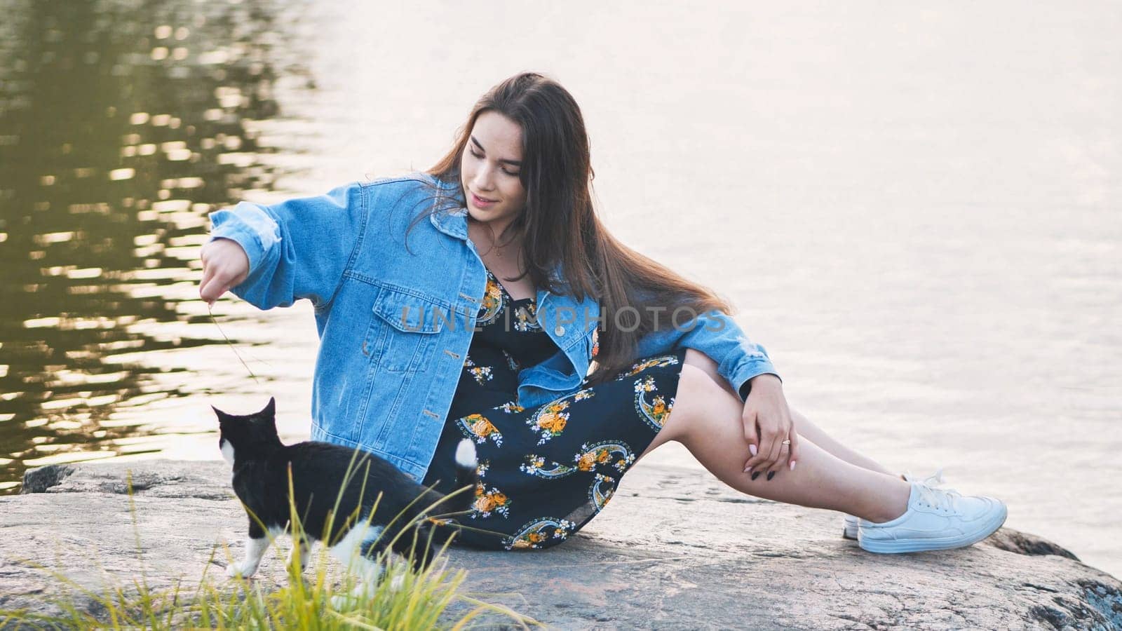 A girl plays with a cat by the lake. by DovidPro