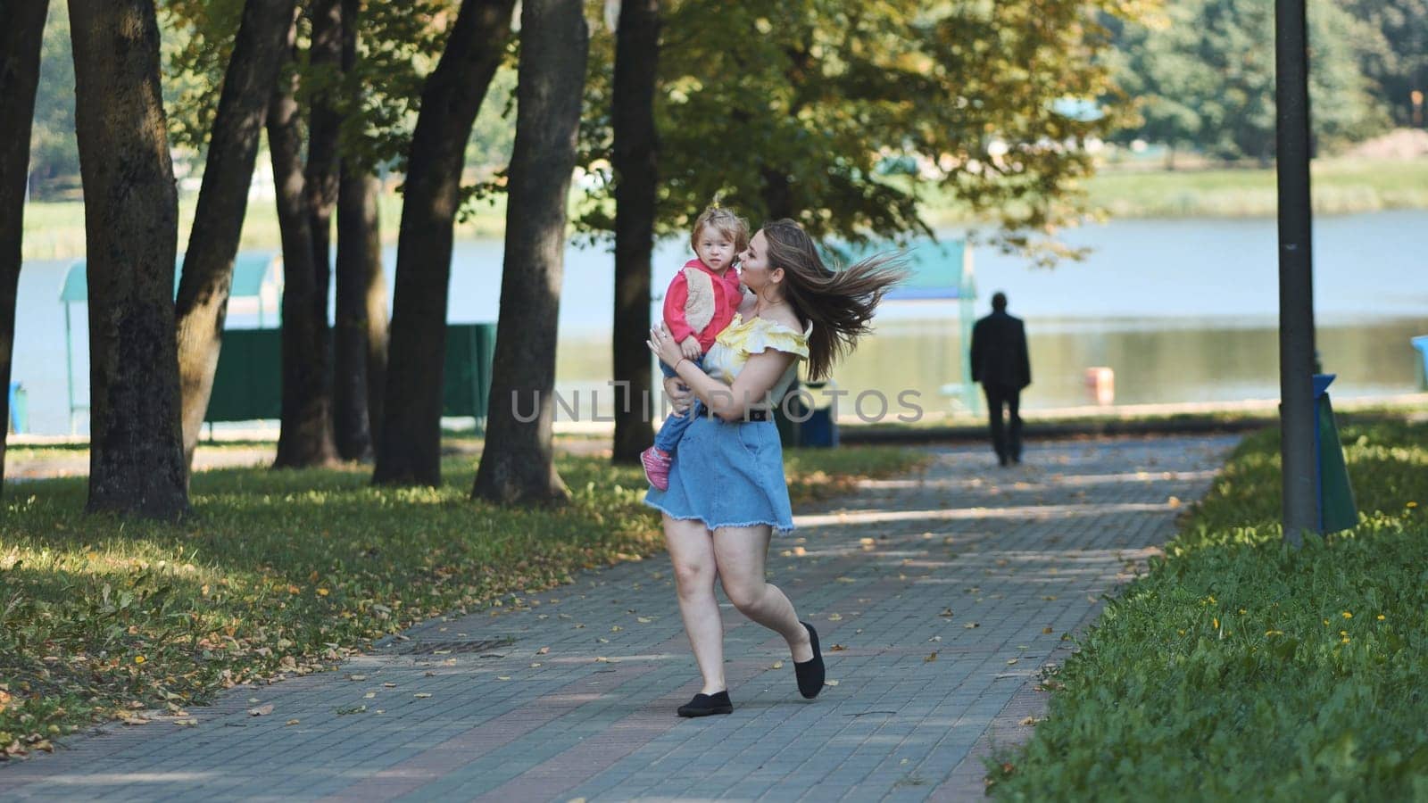 A young mother walks with her daughter in the park