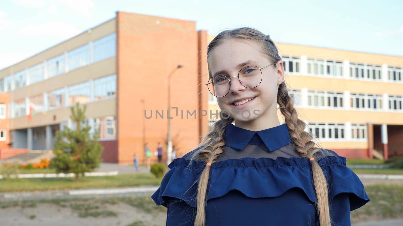 A teenage girl wearing glasses in front of a school. by DovidPro