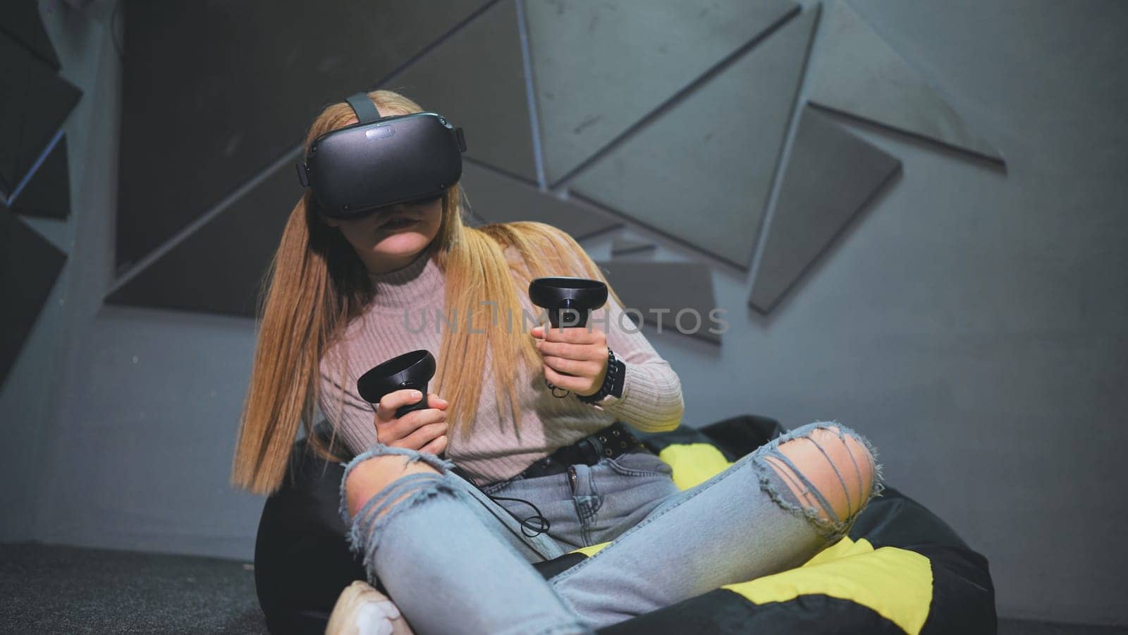 A teenage girl sits in a club with virtual glasses and plays. by DovidPro