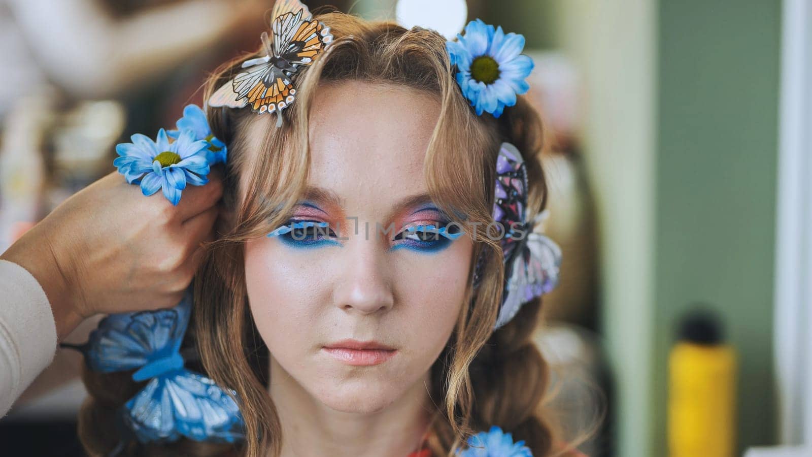 The hairdresser decorates the model's hair with blue flowers and butterflies. by DovidPro
