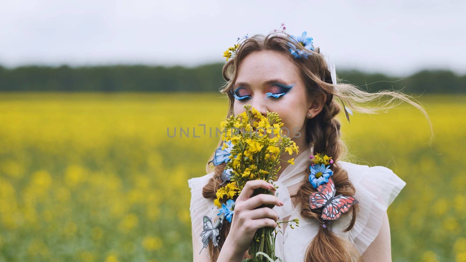A young girl poses in a rapeseed field with a beautiful hairdo of flowers and butterflies. by DovidPro