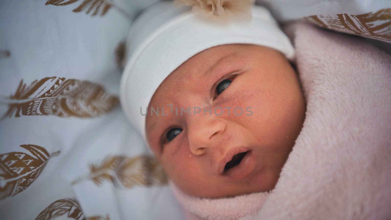 A newborn baby wrapped up in a maternity hospital and looking fo by DovidPro