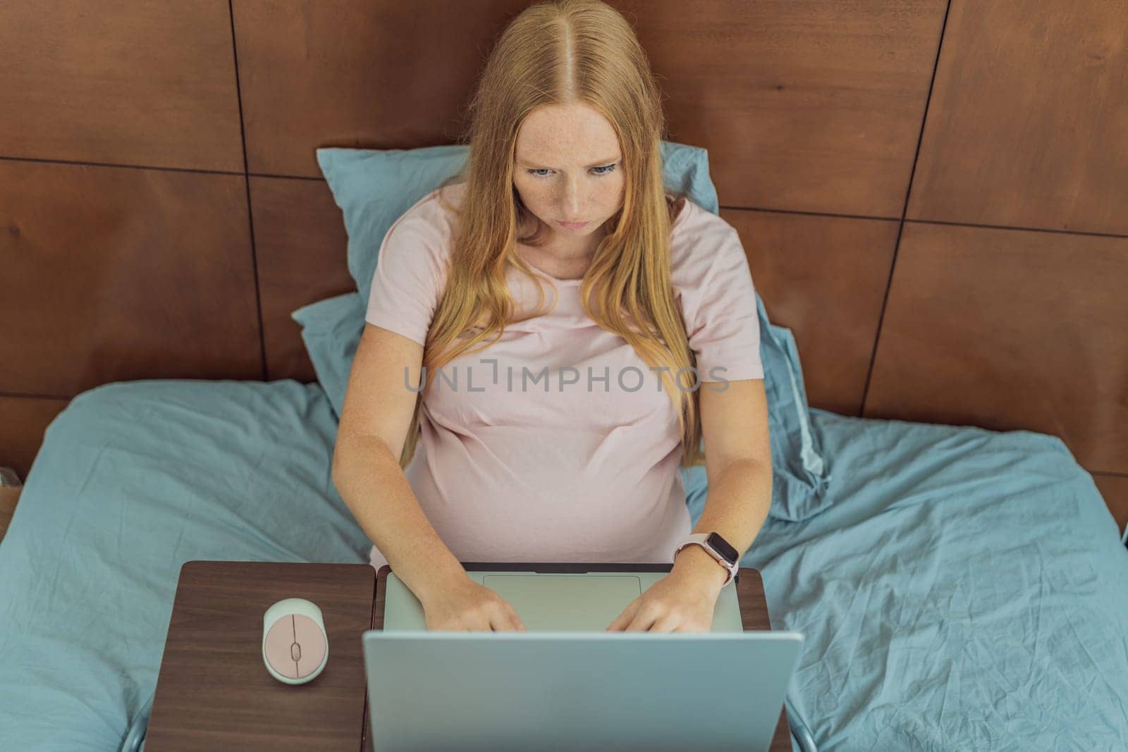 Pregnant woman working on laptop. Expectant woman efficiently works from home during pregnancy, blending professional commitment with maternal duties by galitskaya