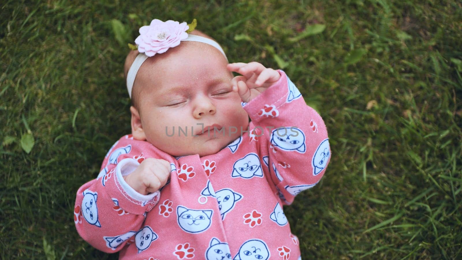 A small child lies on the grass in the summer