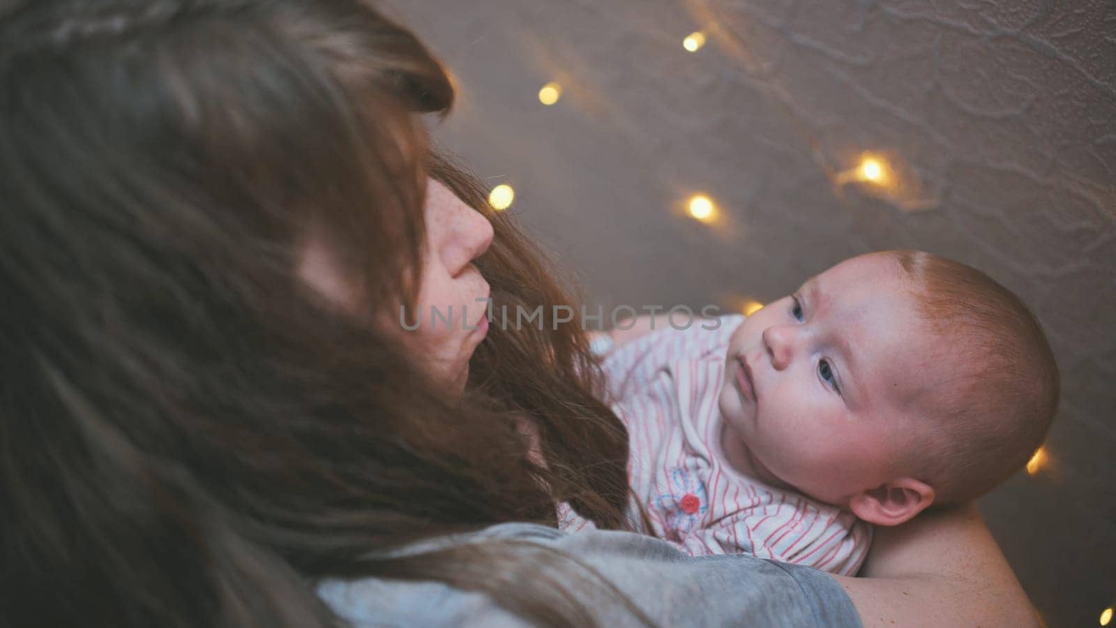 A loving mother with her baby in her arms against a backdrop of lights