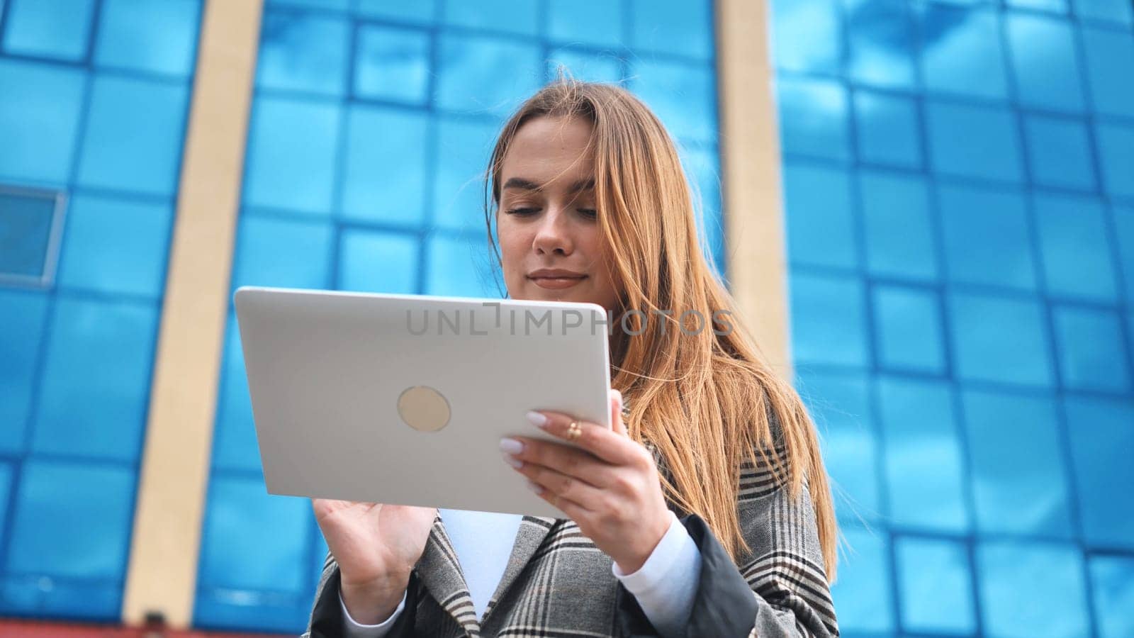 A young girl student works with a white tablet in the city