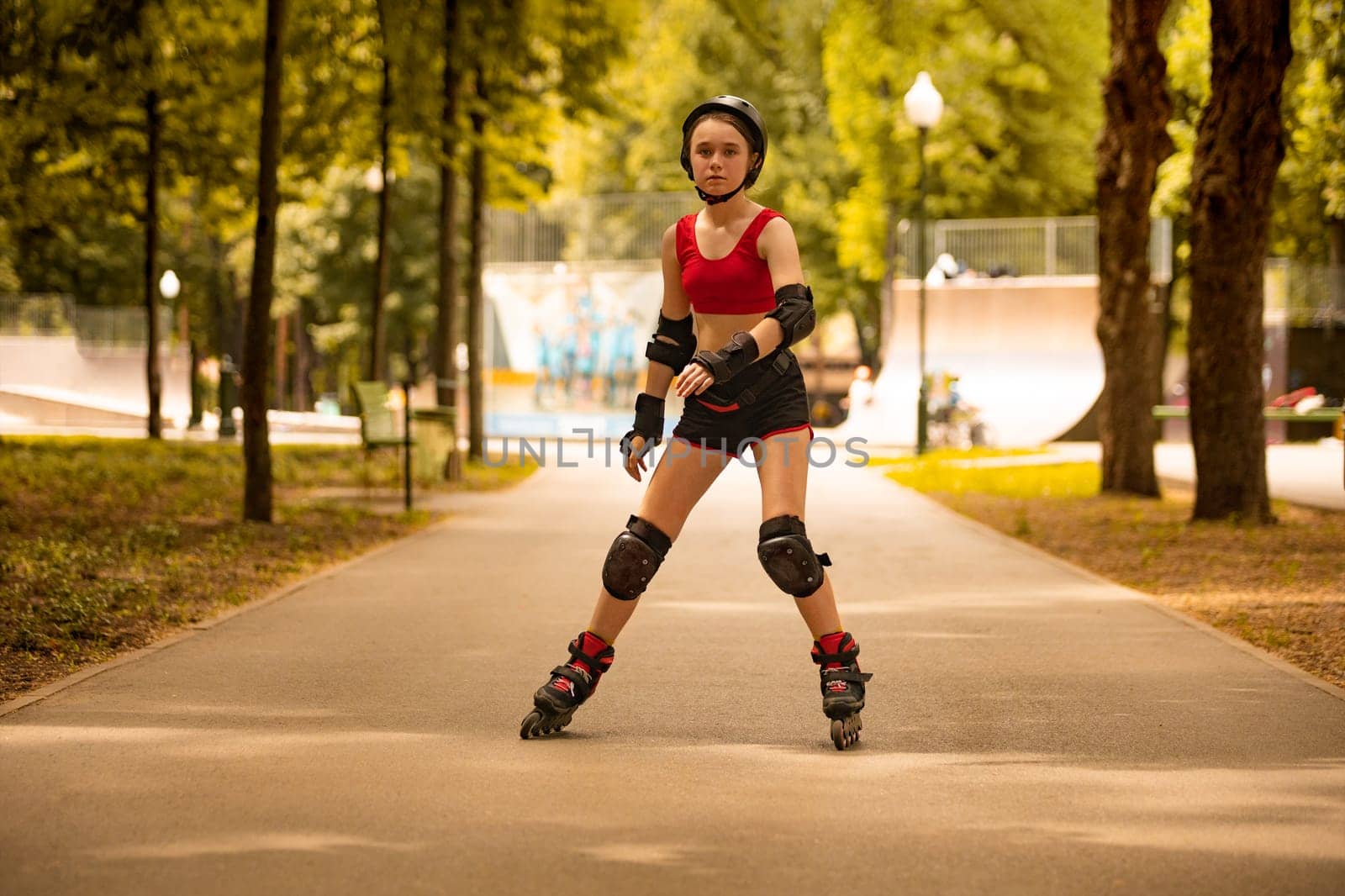 Roller skating girl kid in park rollerblading on inline skates. Caucasian young woman in outdoor activities. by MikeOrlov