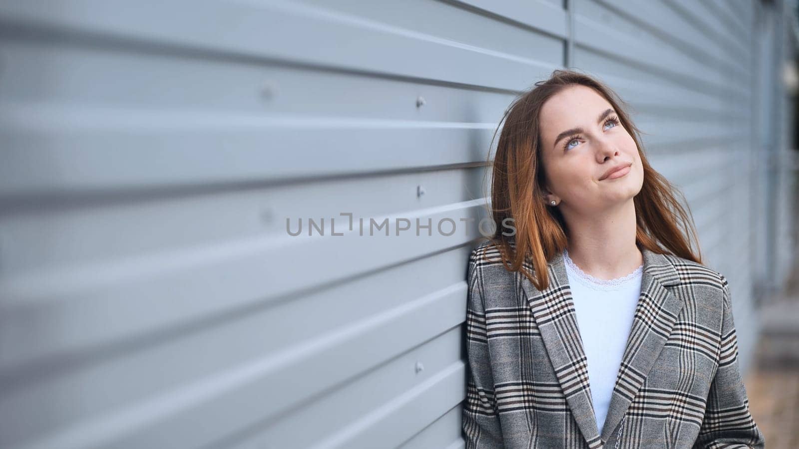 Portrait of a young business girl against a wall on the street