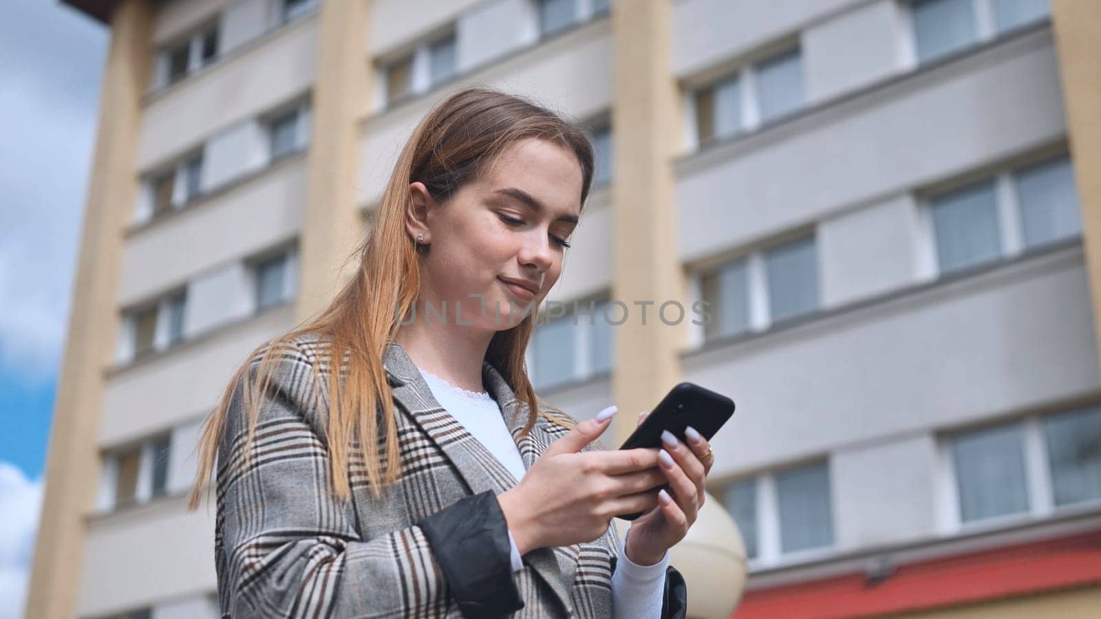 A girl walks through town and looks at her smartphone