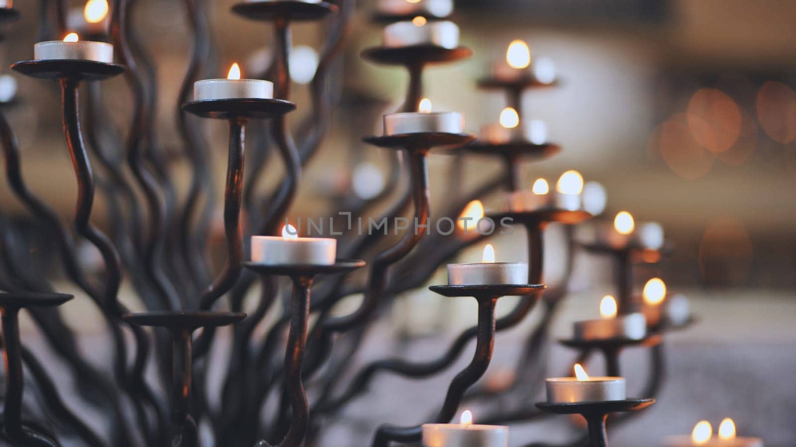 Candlestick holder with burning candles in a Catholic church. by DovidPro