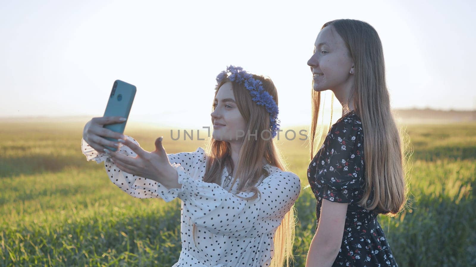 Two Ukrainian girls posing for selfies in a field. by DovidPro