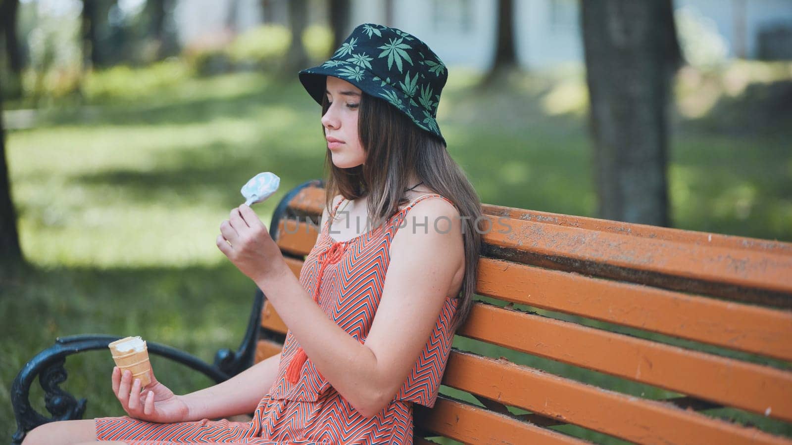 Teenage girl eating ice cream in the park on the bench