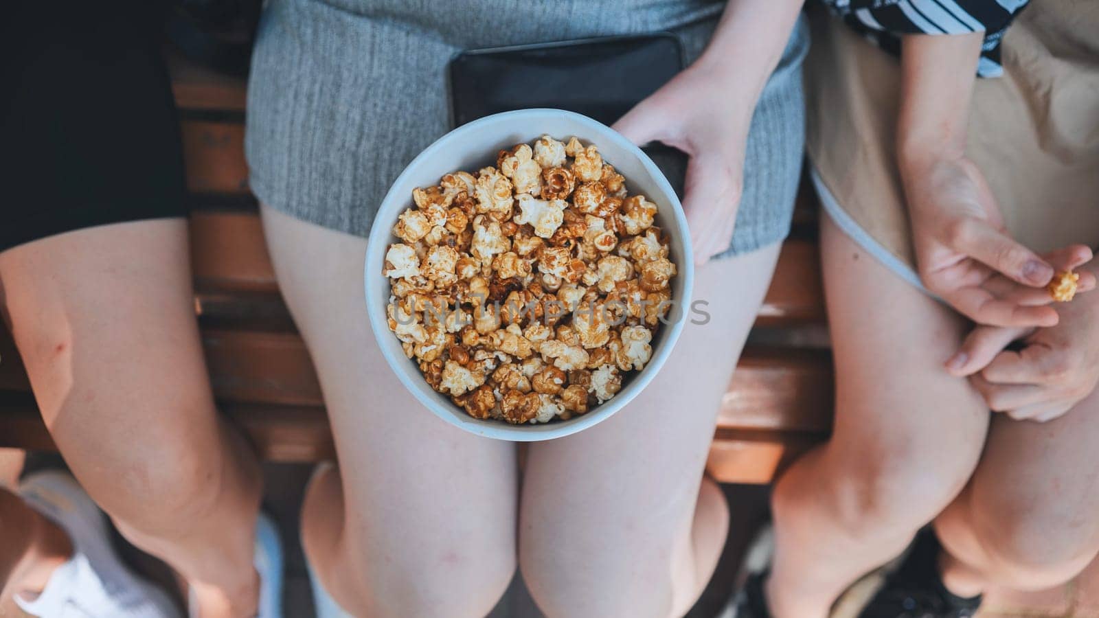 Friends eating popcorn on the street. Close-up of hands