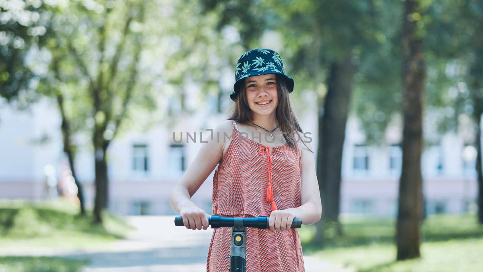 Portrait of a girl on an electric scooter posing in a park in the summer