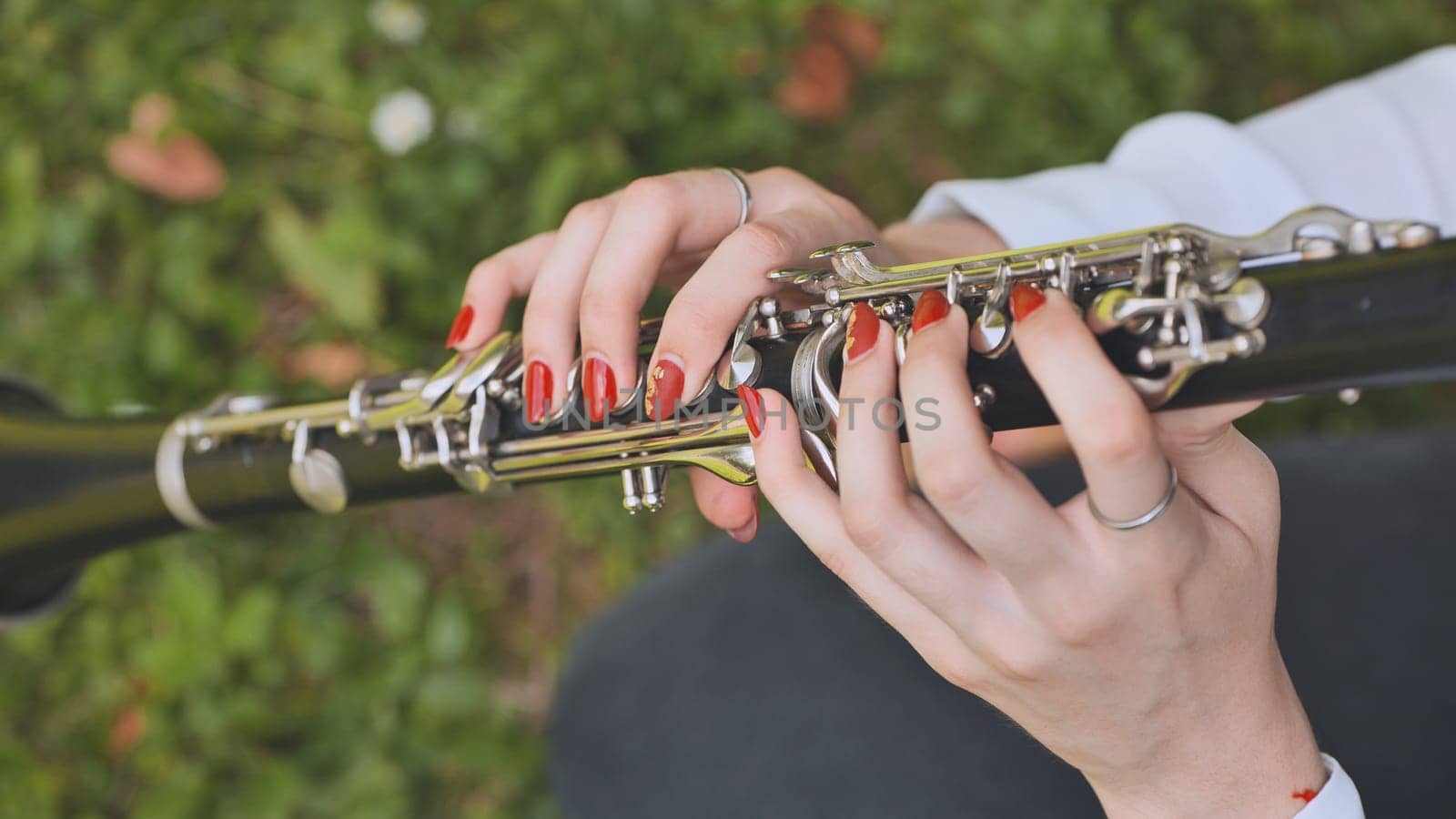 A girl plays the clarinet in the summer in the park. Close-up of her hands