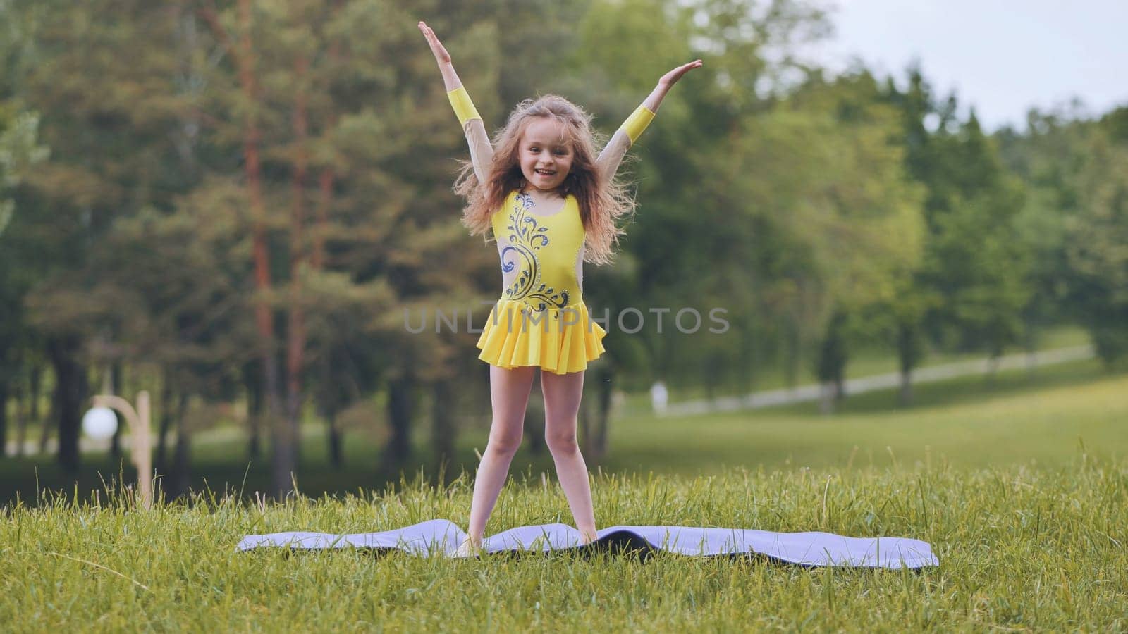 A little girl performs the elements of rhythmic gymnastics in the park