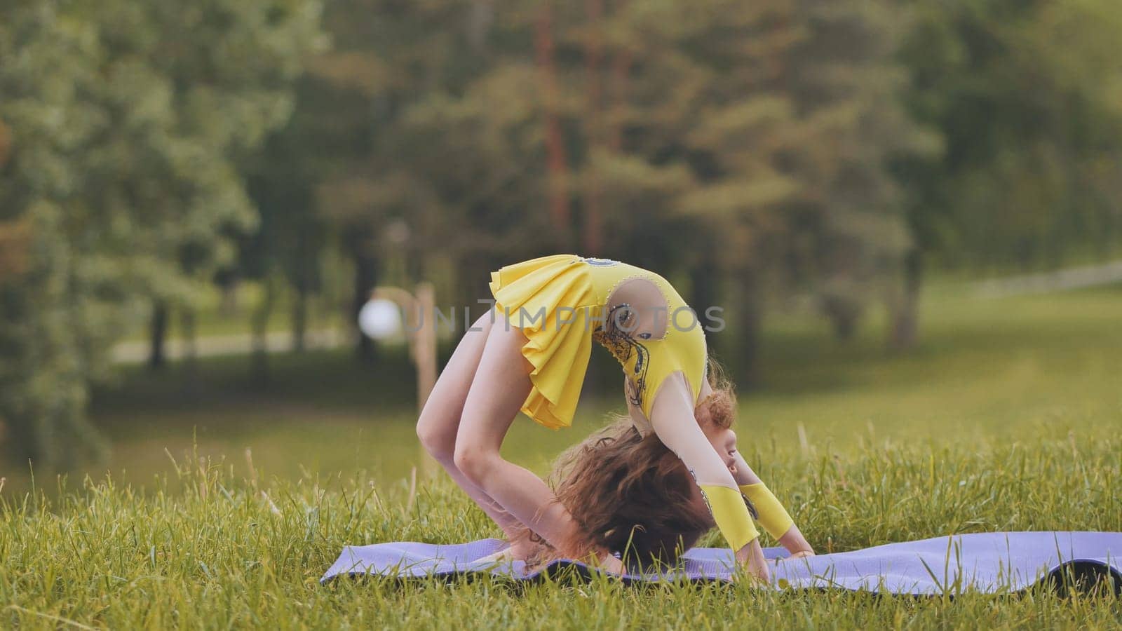 A little girl performs the elements of rhythmic gymnastics in the park