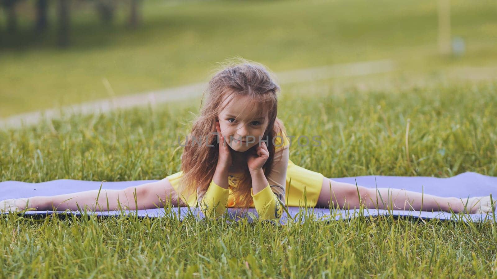 The little girl performs an element of rhythmic gymnastics - splits in the park