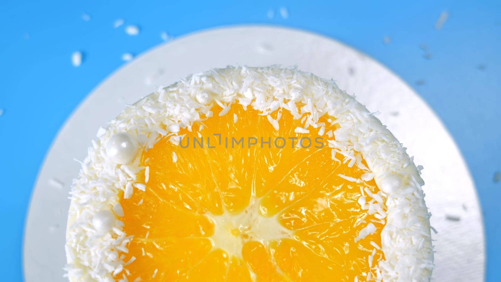Cake with orange and coconut shavings spinning on a blue background. by DovidPro