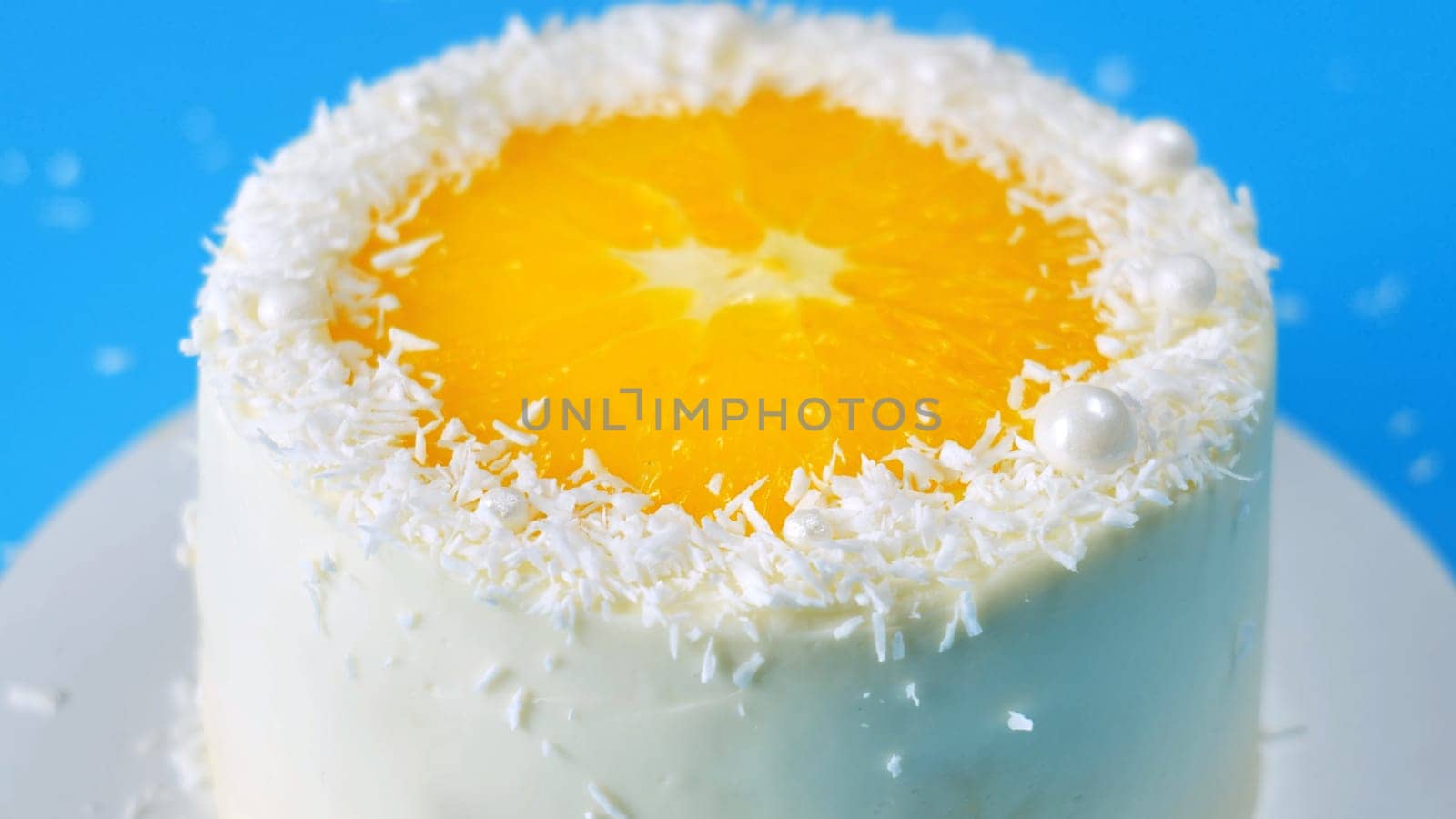 Cake with orange and coconut shavings spinning on a blue background