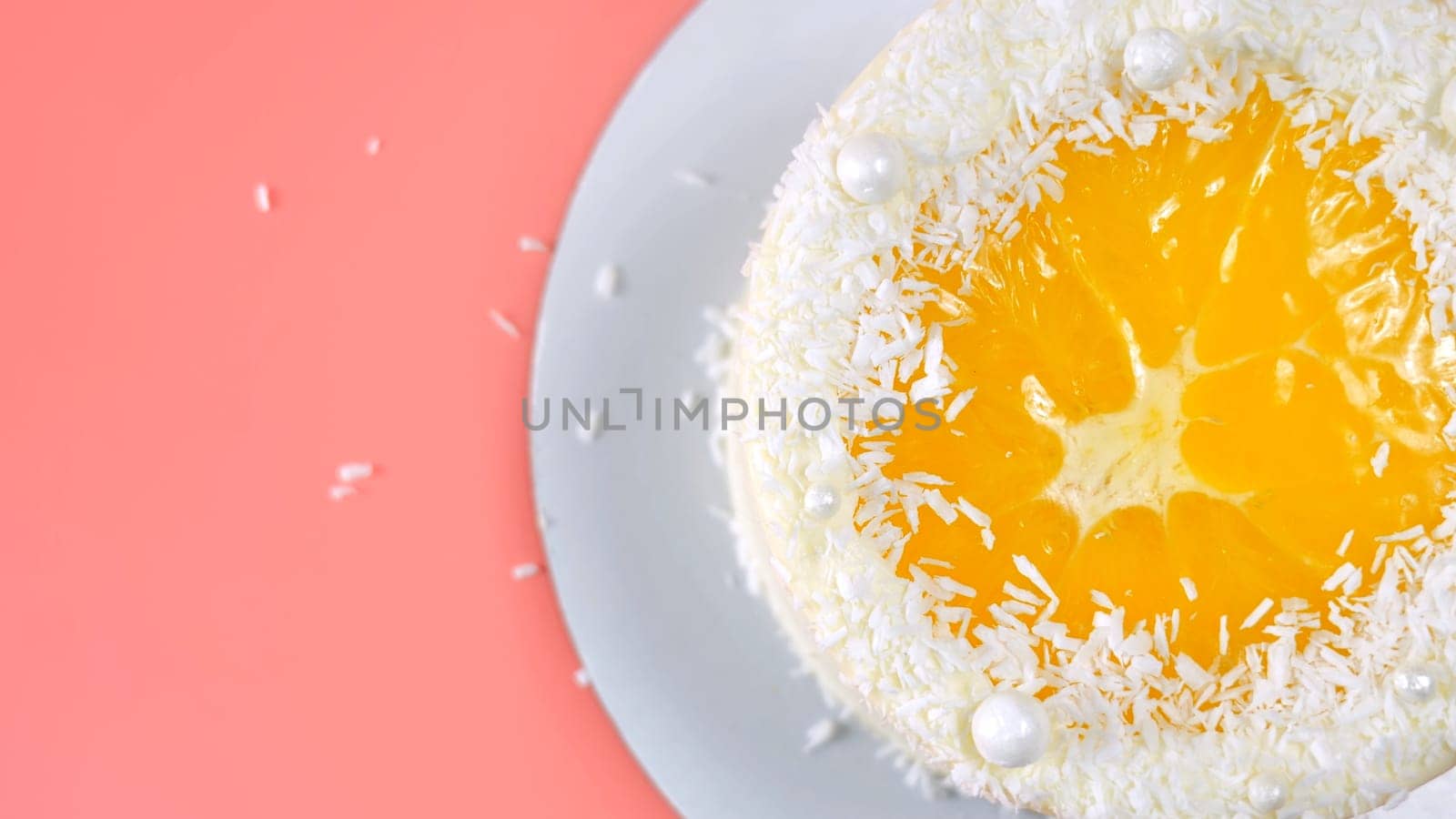 Cake with orange and coconut shavings spun on a pink background. by DovidPro