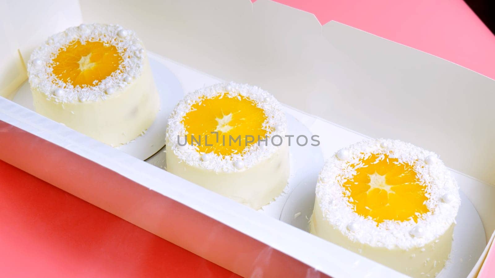 Small cakes with orange and coconut shavings in a box. by DovidPro