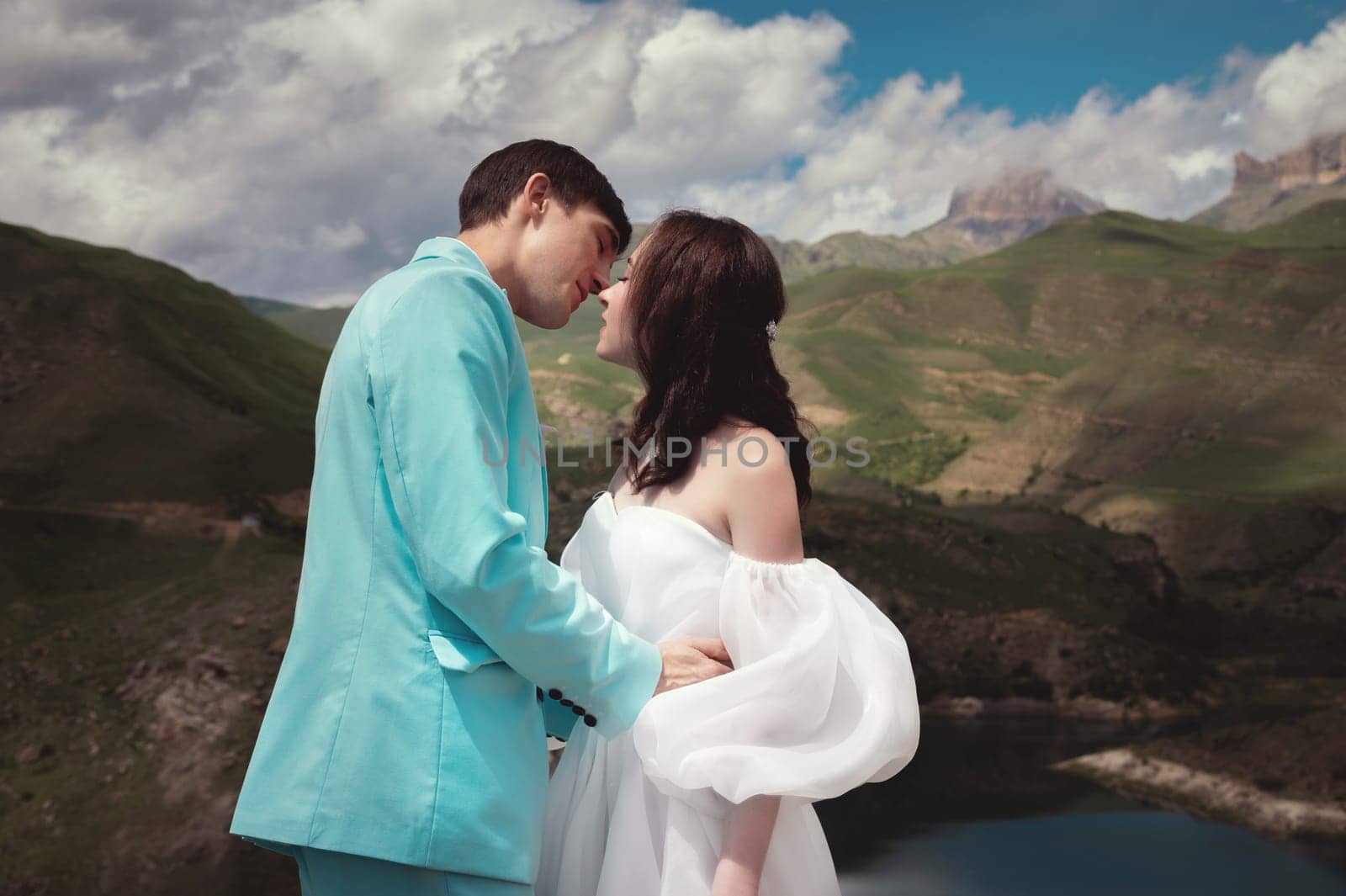 Love, wedding and married couple kissing by the lake outdoors in honor of their romantic marriage. Water, summer, mountains or a kiss.