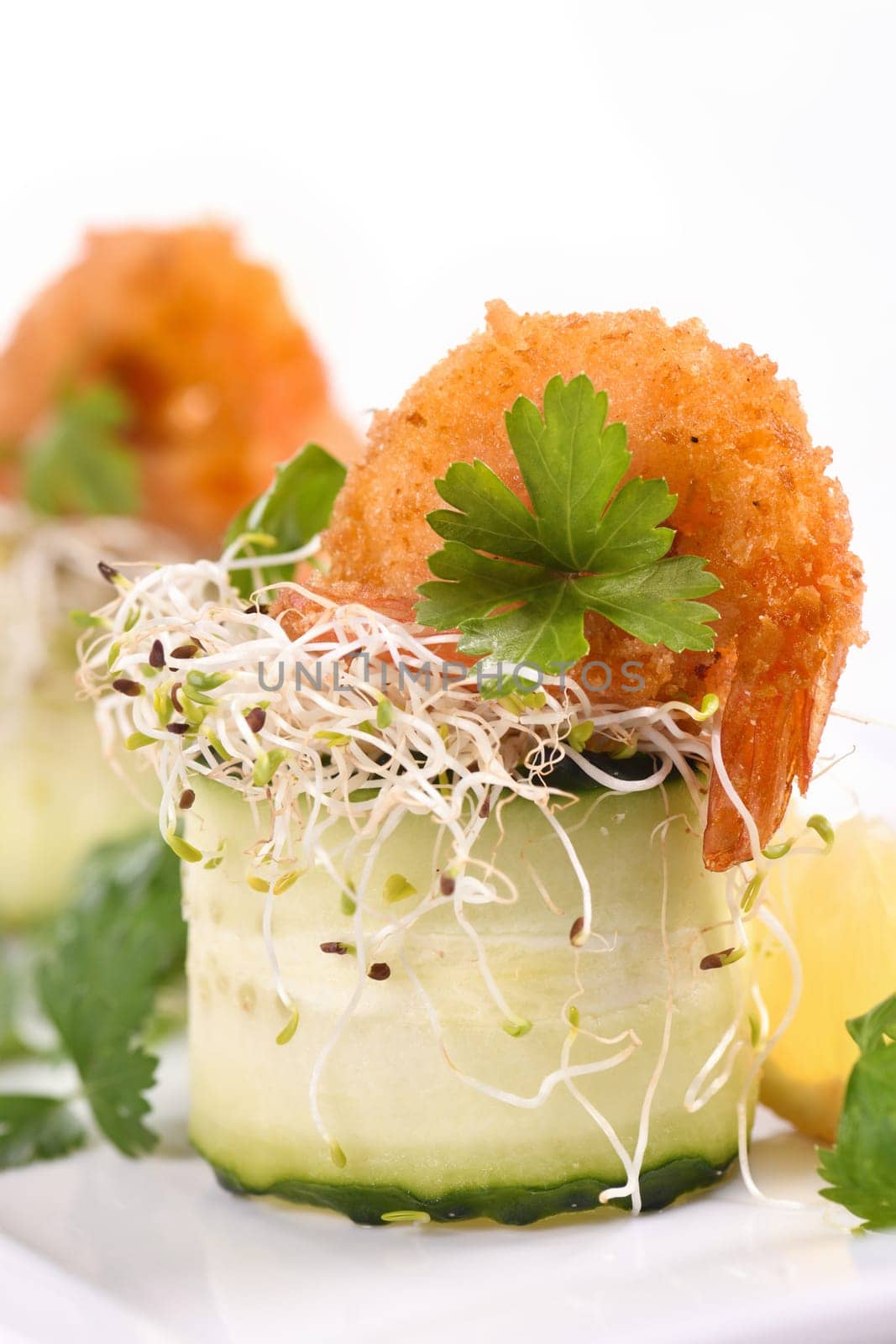 Cucumber appetizer with fried breaded shrimp on a bed of microgreens