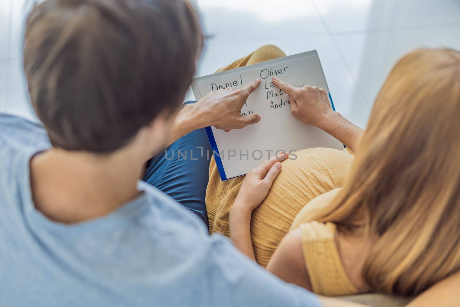 Expectant couple joyfully selects a name for their unborn son, savoring the special moment of choosing a meaningful identity for their growing family.