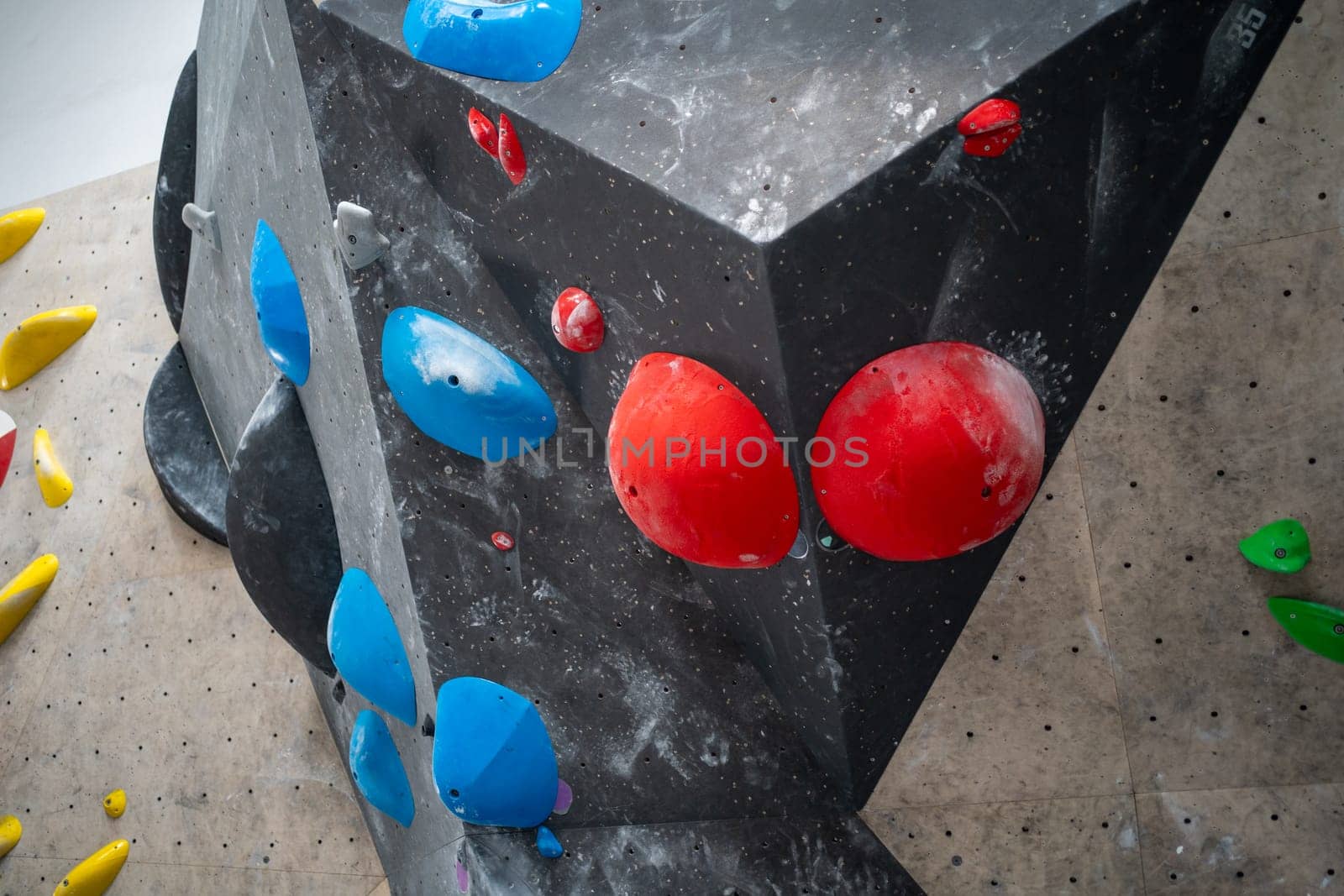 Red and blue grips on black artificial wall climbing in sports center by andreonegin