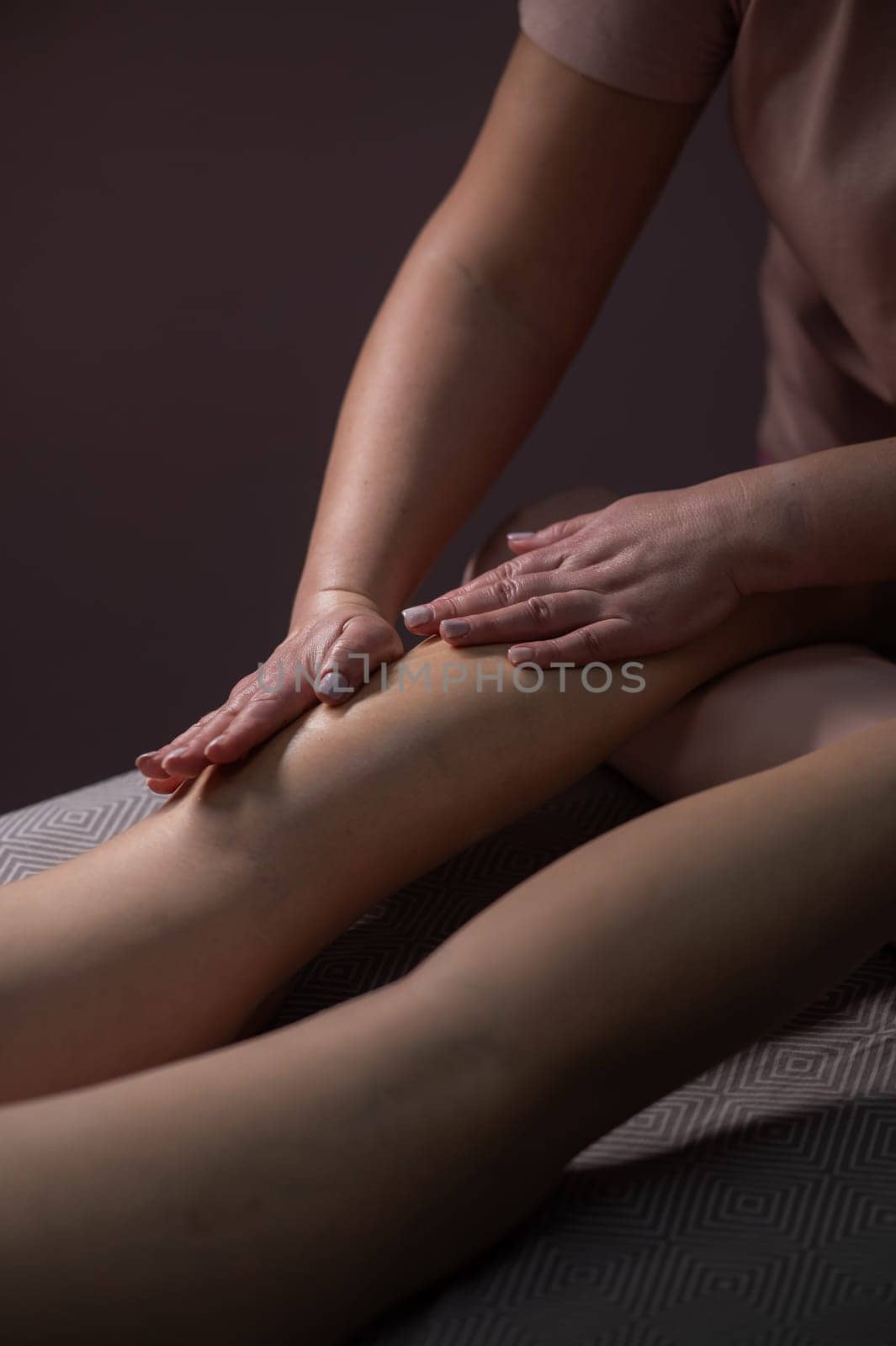 Close-up of a woman's leg massage in a salon. Vertical photo