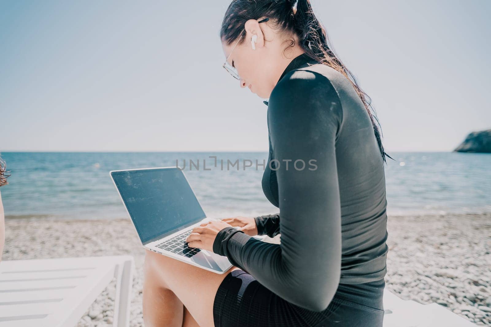 woman laptop sea. Working remotely on seashore. Happy successful lady, freelancer working on sea beach, relieves stress from work to restore life balance. Freelance, remote work on vacation by panophotograph