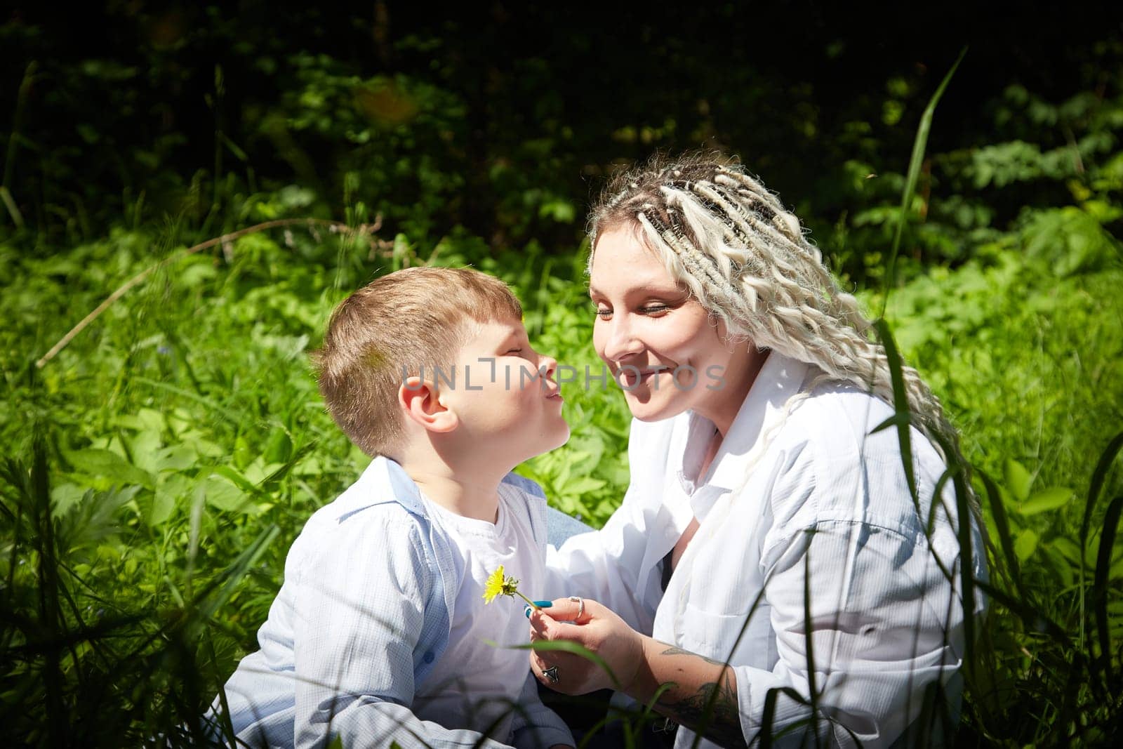 Funny mother with dreadlocks and fat boy happy walking in the forest on a sunny summer day